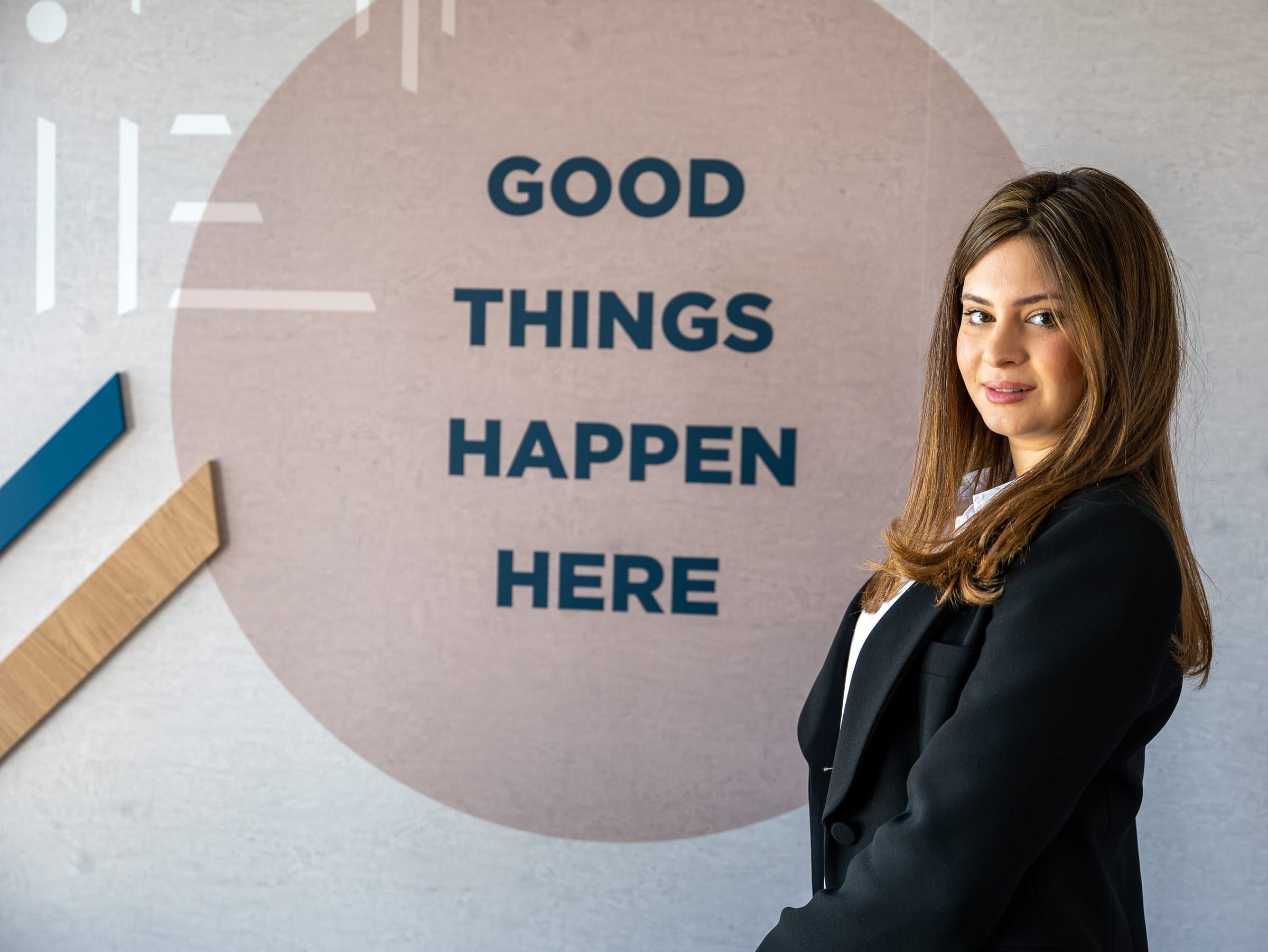 אשת עסקים ליד שלט Good Things Happen Here